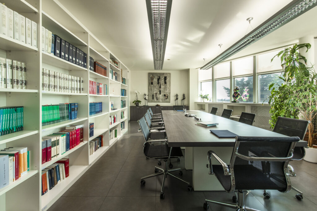 Foto di una sala degli uffici dello Studio Picchi Angelini & Associati, con una grande tavolo e un'ampia parete su cui è posta una libreria